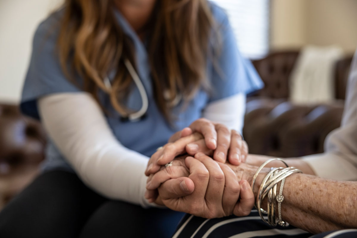 nurse of home health care in McAllen holding a elderly persons hand