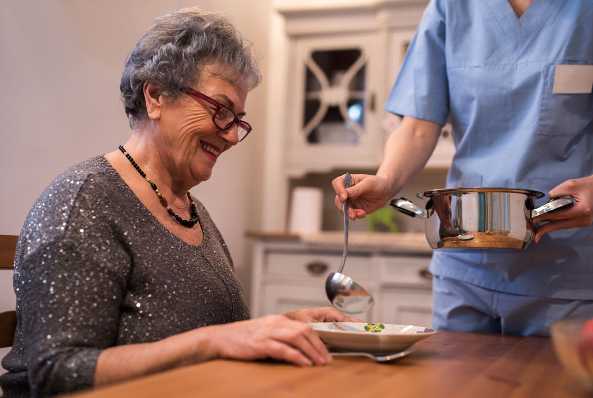 elderly woman being fed dinner by nurse in home care in McAllen